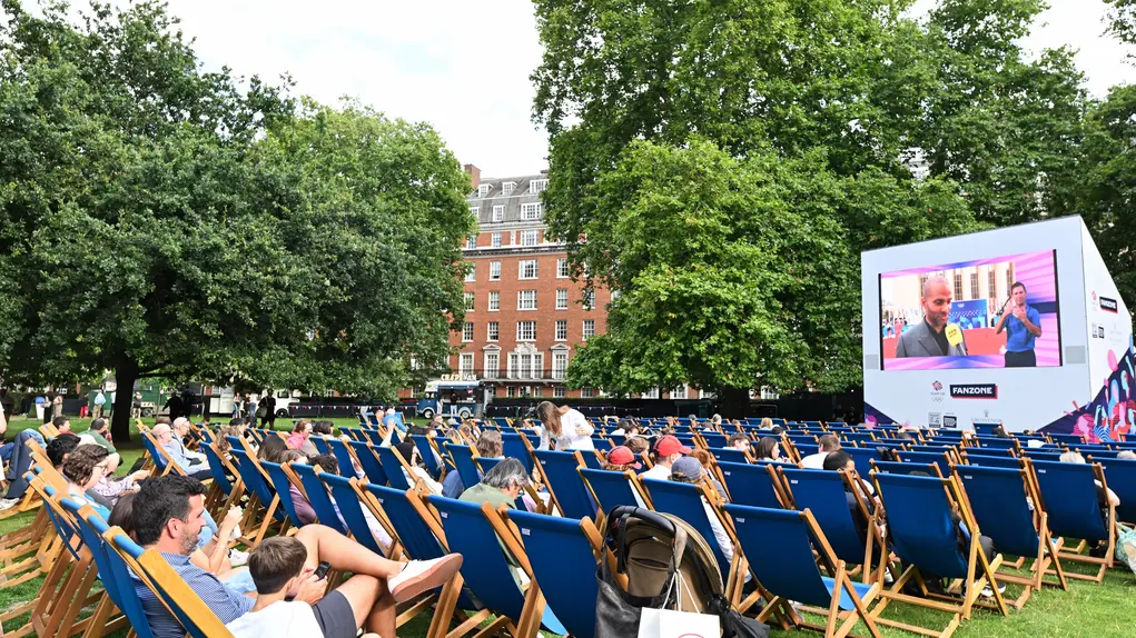 People sitting on deckchairs watching sport on a big screen