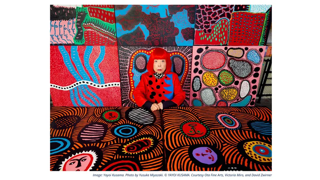 Yayoi Kusama sitting alongside her colourful patterned artworks