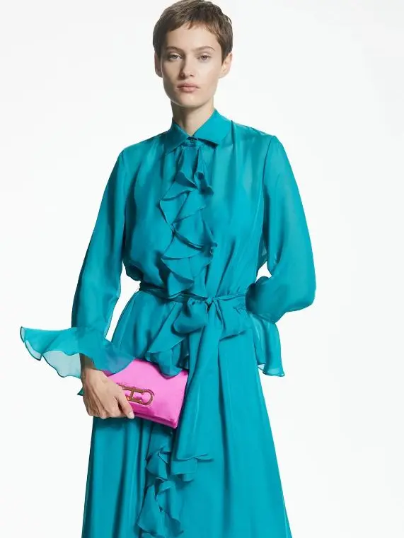 A woman in a blue ruffly dress and a pink handbag