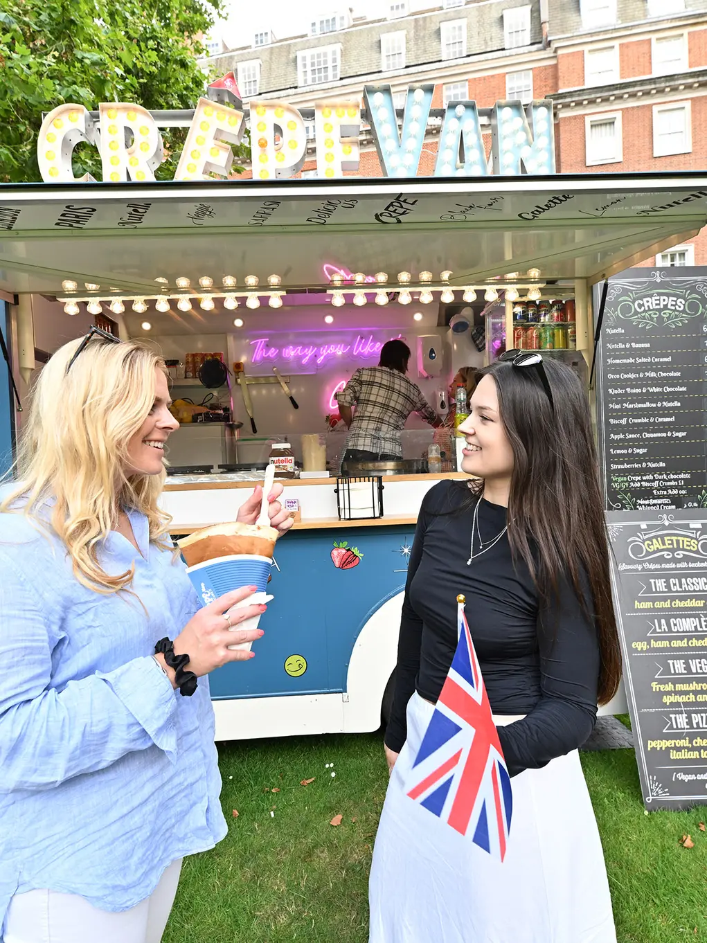 Two women standing in front of a crepe van