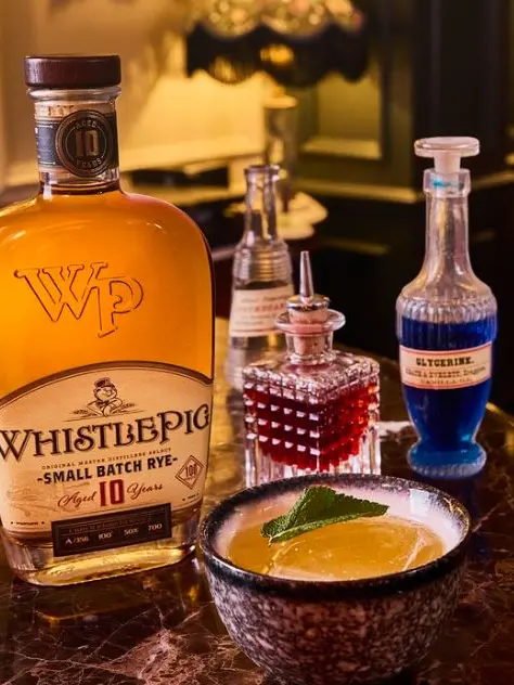 A bottle of Whistlepig whiskey and three other bottles filled with drinks