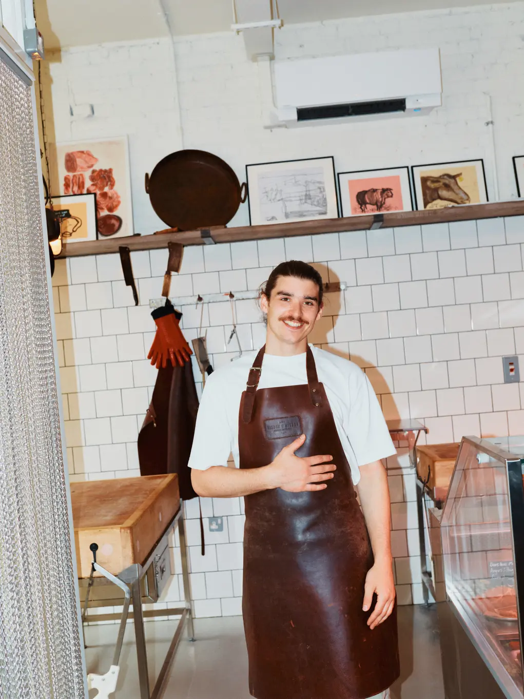 Harvey Baker wearing an apron in a butcher shop