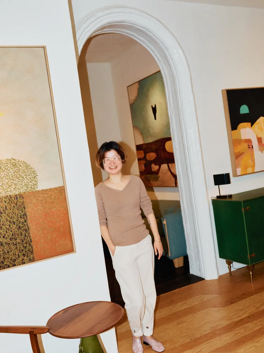 Vicki Sun standing in a doorway with artworks either side