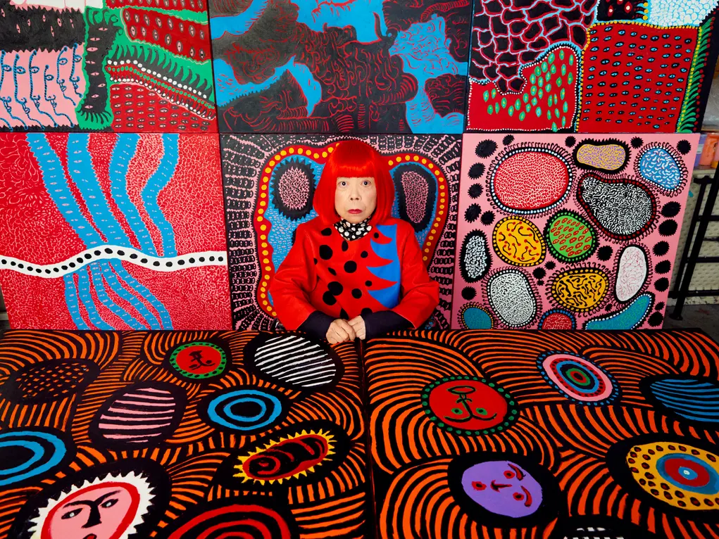 Portrait of Yayoi Kusama surrounded by colourful artworks